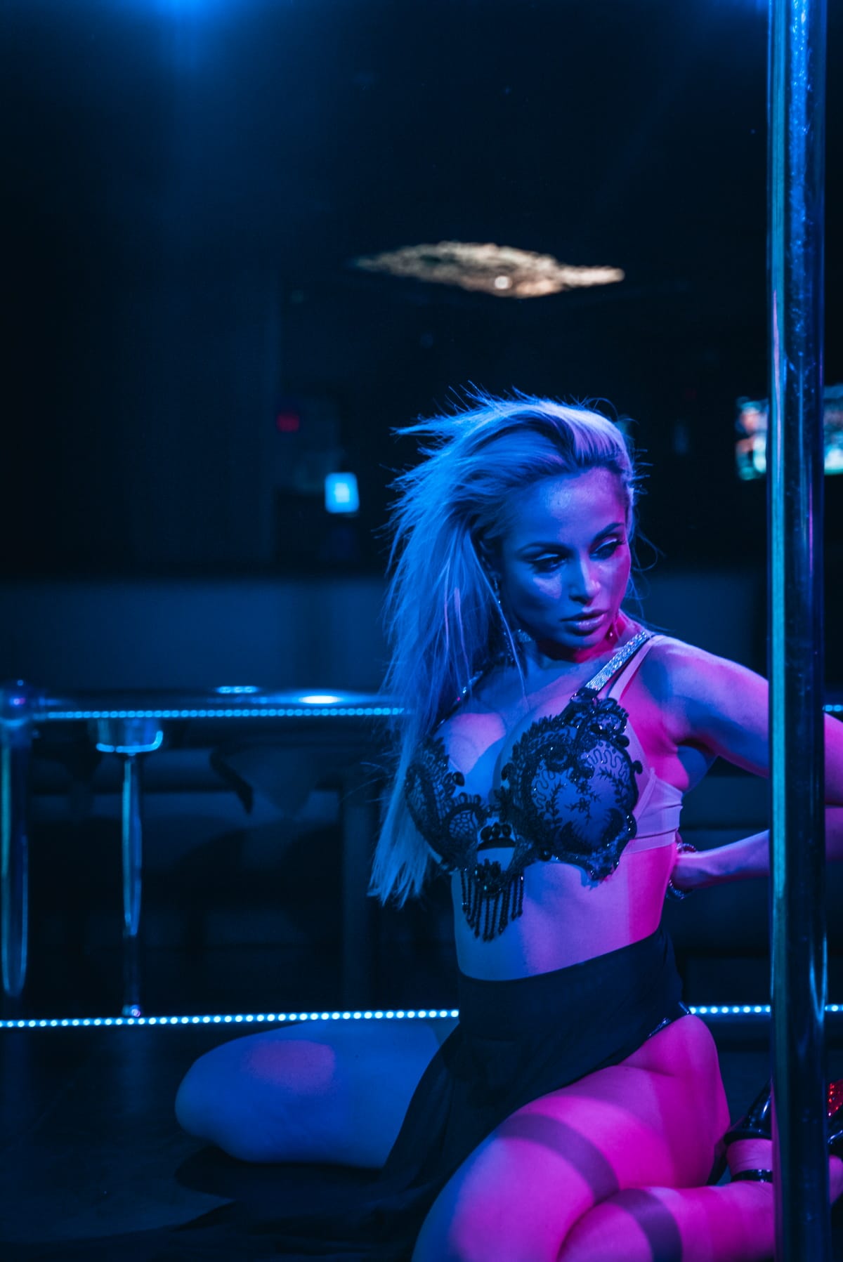 Blond woman in black bra top and skirt sitting on a pole at a strip club party in Las Vegas.